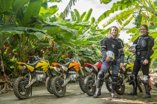 Two foreign gils are posting with banana grove and the motocross